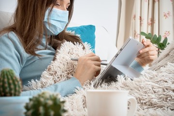 Work from home at the quarantine.Sick woman in nose guard runs business from home. Remote work on the internet during sick leave or self isolation