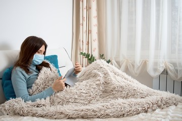 Work from home at the quarantine.Sick woman in nose guard runs business from home. Remote work on the internet during sick leave or self isolation
