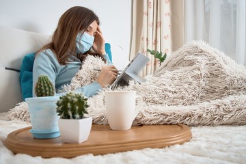 Work from home at the quarantine.Sick woman in nose guard runs business from home. Remote work on the internet during sick leave or self isolation
