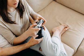 Close-up of young couple of man and woman playing video game on a console, sitting on couch in living room.