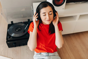 Close-up portrait if a young brunette woman with eyes closed, wearing red t-shirt, sitting on the...