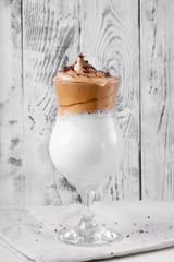 Whipped dalgona coffee in a tall glass against the white wooden background - 343173671