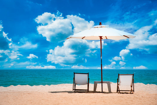 Two beach chairs and white umbrella on the tropical beach at daytime
