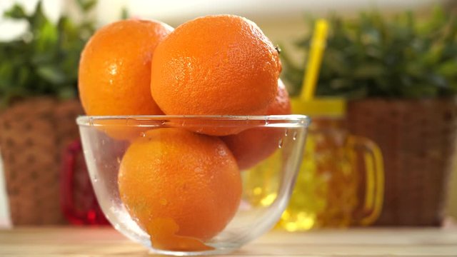 Hands put on a table a plate with oranges. 
Quick refocus with colorful mugs on oranges.