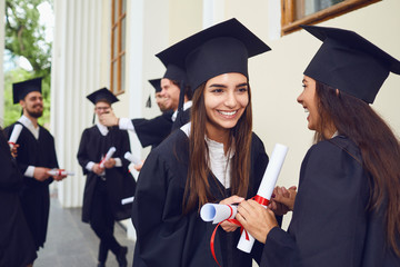 Female graduates with diplomas in their hands hugging