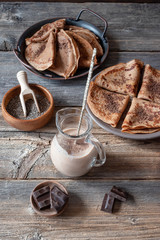 Oat milk with chia seeds and chocolate pancakes for breakfast on a wooden background. Proper nutrition concept.