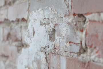 Old brick wall with white paint background texture close up. Side view, low depth of field.