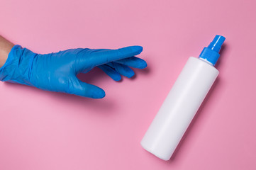 Coronavirus protection. Hand in blue disposable glove reaching for spray bottle of surface...