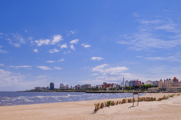 Montevideo beach with sand fence barriers and skyline on a sunny day, Montevideo, Uruguay