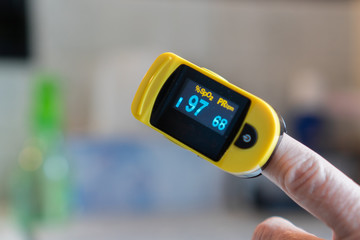 Close-up of hand with pulse oximeter attached to finger measuring blood oxygen and pulse rate