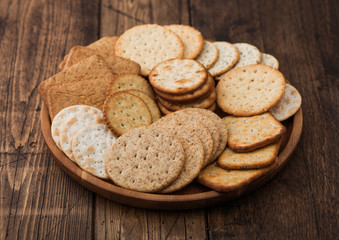 Fototapeta na wymiar Various organic crispy wheat, rye and corn flatbread crackers with sesame and salt in round plate on wooden background.