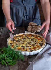 Quiche with champignons. Hands in the frame. Vertical photo.