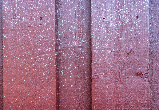 Close up view at multiple small white spots of white paint accidentally sprayed at red weooden wall.