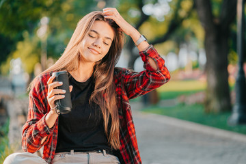 Modern trendy girl listening to music by wireless portable speaker.Young beautiful american woman...
