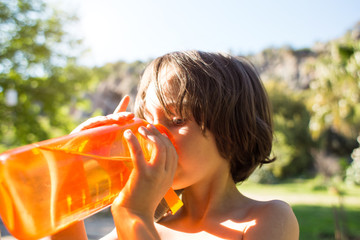 A child drinks water from a refillable bottle on a hot summer day.