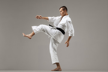 man exercising karate, against gray background