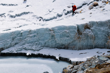 Man trekking over glacier next to frozen lake