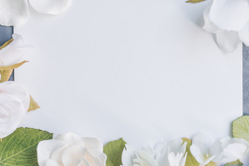 delicate white flowers and roses around. White sheet of paper for inscription on a gray background, copyspace