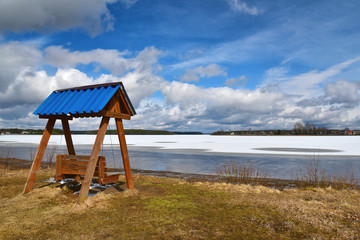 Swing on the shore of a frozen lake on a sunny spring day