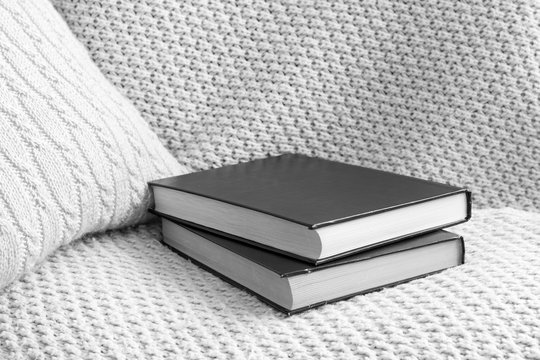 Two books and small decorative pillow on knitted woolen bed cover. Leisure time motif