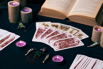 Candles and old tarot cards on dark silk. Halloween and fortune telling concept. Mystic background with occult and magic objects on witch table.