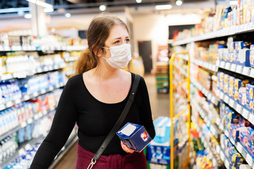 young woman with filtering facepiece in a supermarket