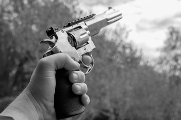 one left hand holds a big silver revolver in the air