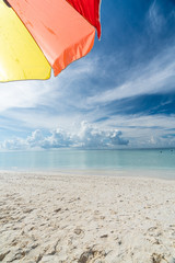 Colorful umbrella on paradise white sand beach and blue sky in sandbank island, Maldives.