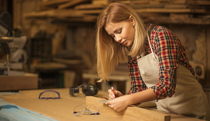 Fototapeta na wymiar portrait of beautiful caucasian woman carpenter dealing with handicraft, woman has own business connected with making wooden furniture in workshop