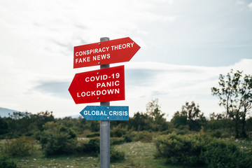 Conspiracy theory, fake news, Covid-19, panic, lockdown, global crisis road warning signs. Social media campaign for coronavirus plus total disorientation an fear in society