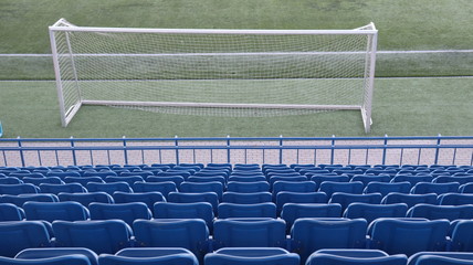 stadium tribunes with football goal on green pitch