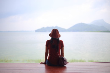 A woman sitting and enjoying the view of the river and mountain