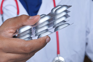 Close up of doctor holding blister pack in hand.