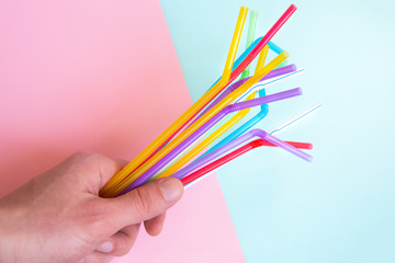 Man holding plastic straws for cocktails. Pastel pink and blue colors. Summer vibes. Hipster party with beverages.