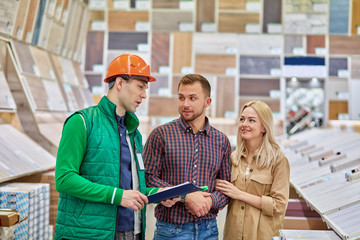 manager of distribution center or warehouse worker help cutomers with choice, married couple came...