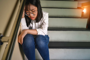 A depressed girl sitting on the stairs in the house