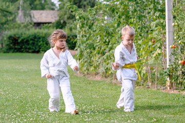 Fototapeta premium Young karate girl and boy train on the grass in backyard of home