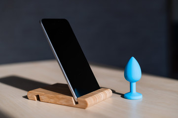 Blue anal plug synchronizing with a smartphone. Latex vibrator delivering for carnal pleasures.