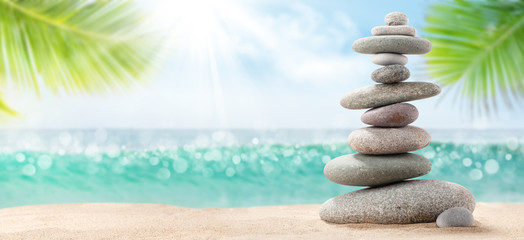 Pyramid of sea pebbles on a sunny sand beach