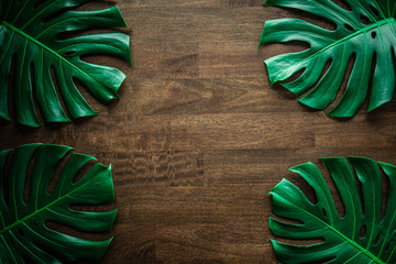 Monstera leaf top view philodendron leaf pattern on old wooden table background, copy space