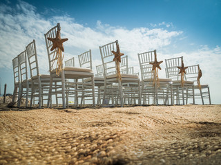 chairs of a romantic white beach wedding celebration with starfish as decoration 