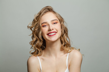Happy woman with long blonde curly hair on white background