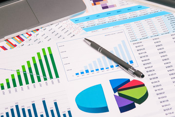 Obraz premium Computer, graphics and pen on the desktop. Research and Analytics in business. The development of enterprise and accounting.
