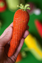 photo knitted carrot in hand on a green background