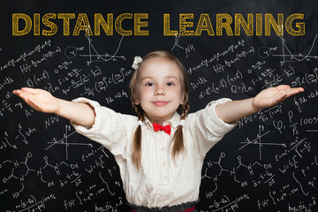 Happy little school girl on blackboard background with maths and art pattern