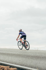 Isolated female road cyclist cycling up the hill