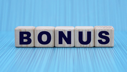 the concept of the word BONUS on cubes on a blue background in a stripe