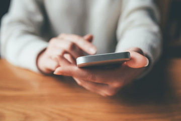 Women's hands use a smartphone for online shopping, social networking, or remote work. Close up image.