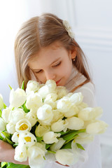 Obraz na płótnie Canvas Portrait of beautiful pretty girl with white flowers tulips. Indoor photo.
