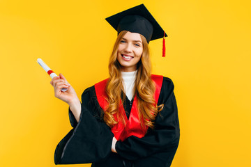 Excited beautiful graduate, with a diploma on a yellow background. Concept of the graduation...